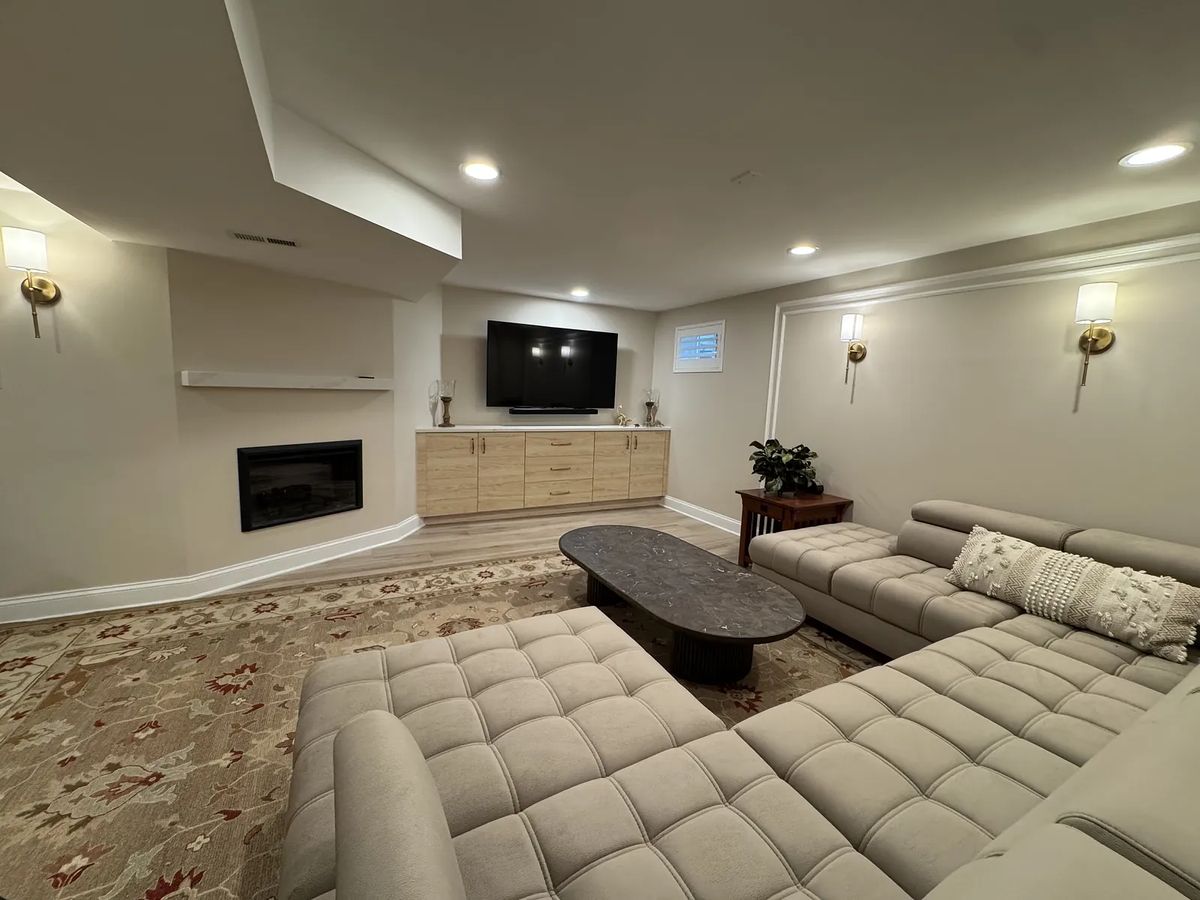 Living room with sectional sofa, coffee table, TV, media console, fireplace, and floral area rug.