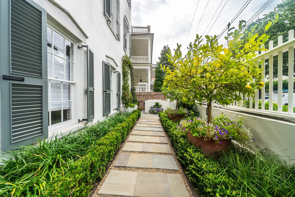 Garden pathway with stone pavers, grass, flowers, and a tree with yellow fruit.