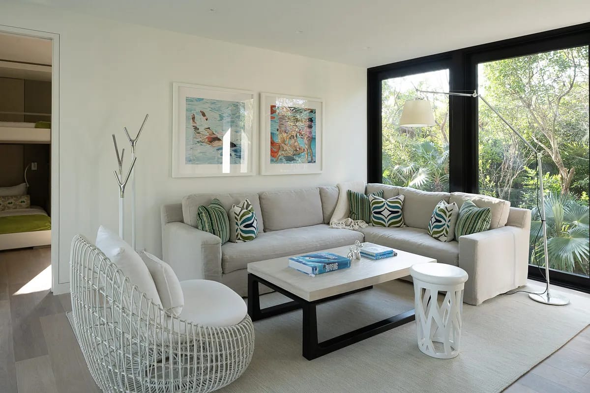 Living room with large sectional sofa, coffee table, accent chairs, wall art, and floor lamp with large windows.