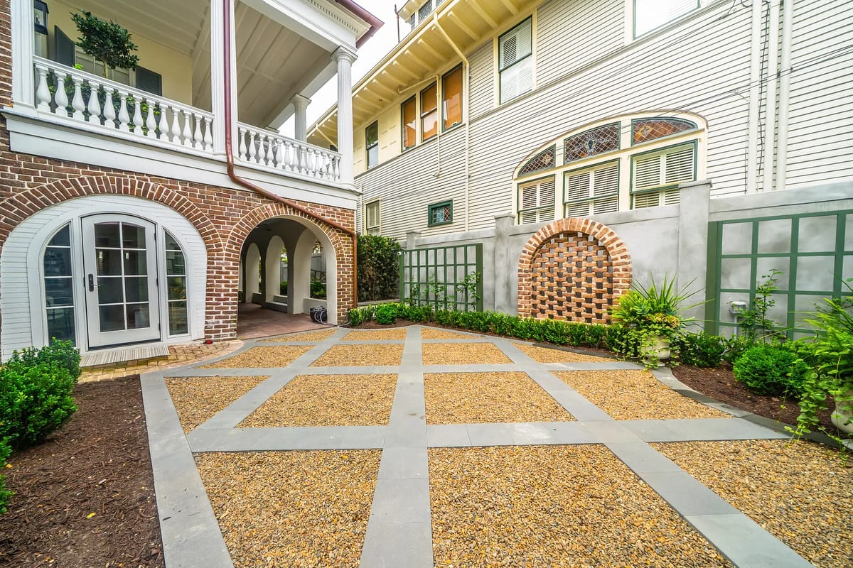 Garden area with stone walkway, gravel pathways, low shrubbery, and curved brick walls.