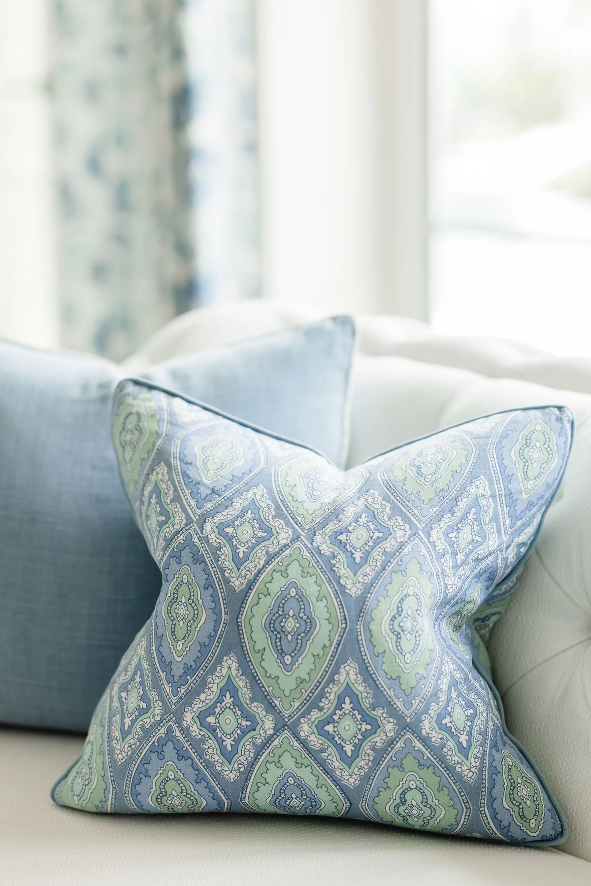 Living room with decorative throw pillows in blue and green patterns and textured sofa fabric.