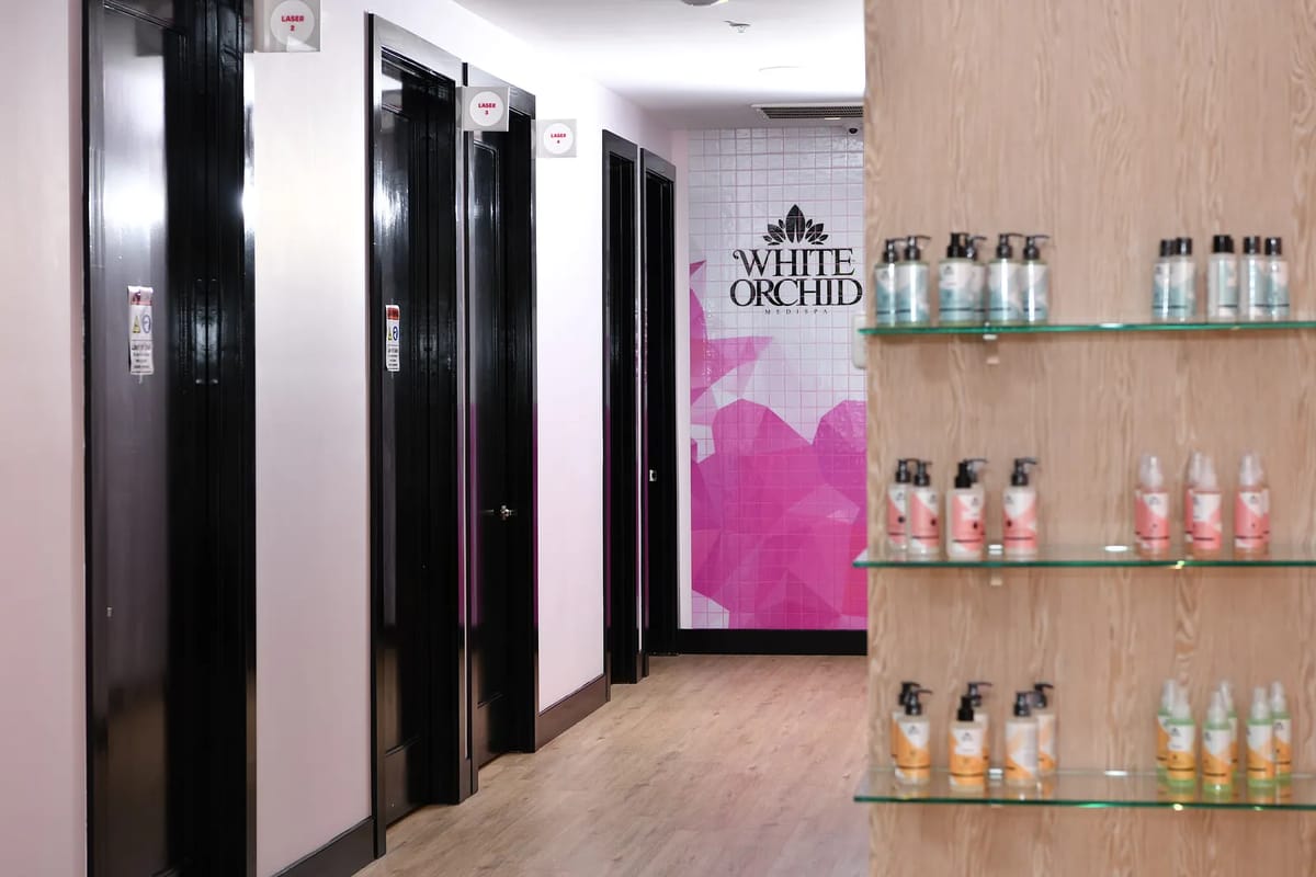 Corridor with black doors, 'WHITE ORCHID' signage, and glass shelf displaying bottles.