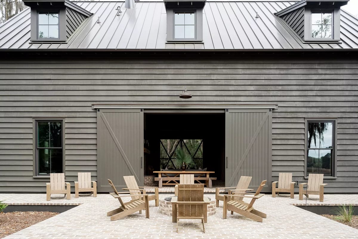 Patio with stone paver floor, wooden chairs around fire pit, and open doorway to interior.