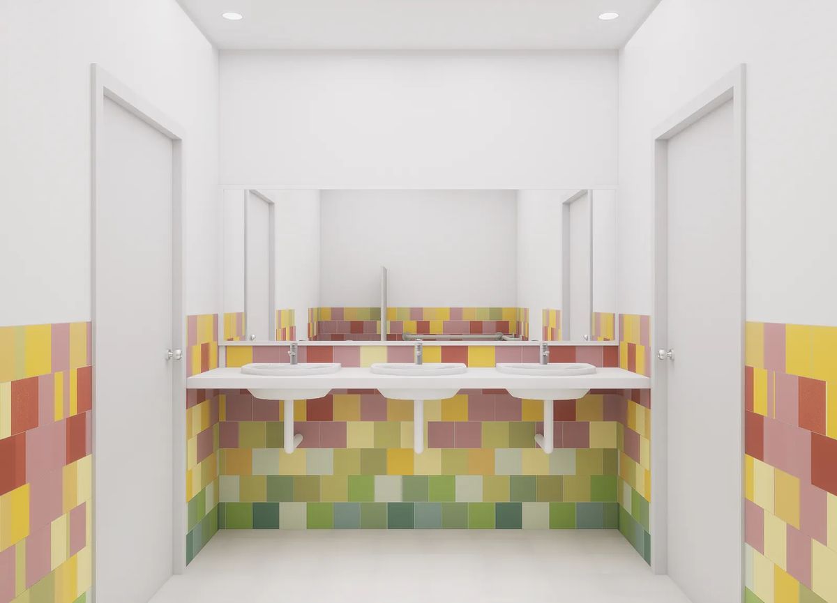 Bathroom with two white basins, large mirrors, and colorful tiled walls in yellow, pink, and green.