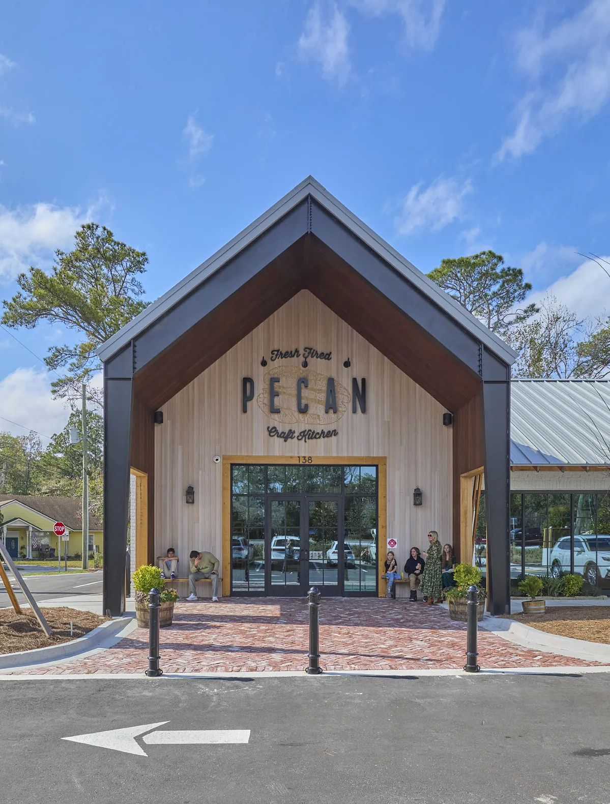Front exterior with A-frame roof, glass entrance, brick pathway, and landscaped areas.