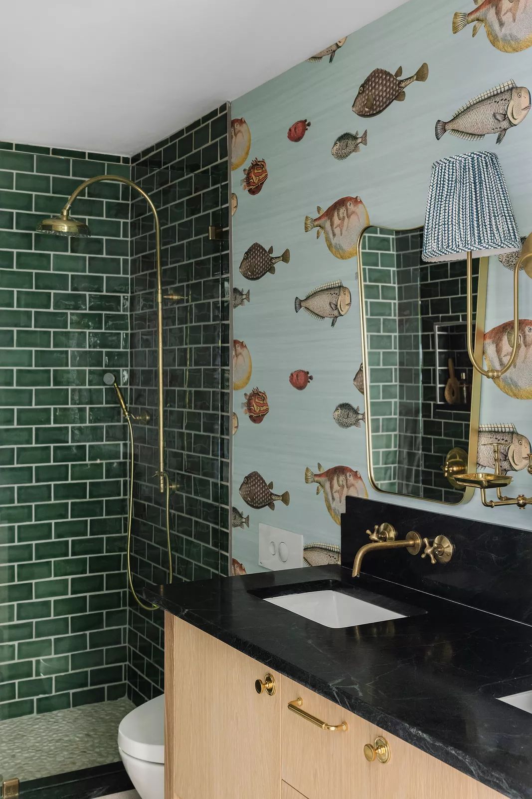 Bathroom with green subway tiles, black countertop, rectangular sink, fish wallpaper, and gold fixtures.