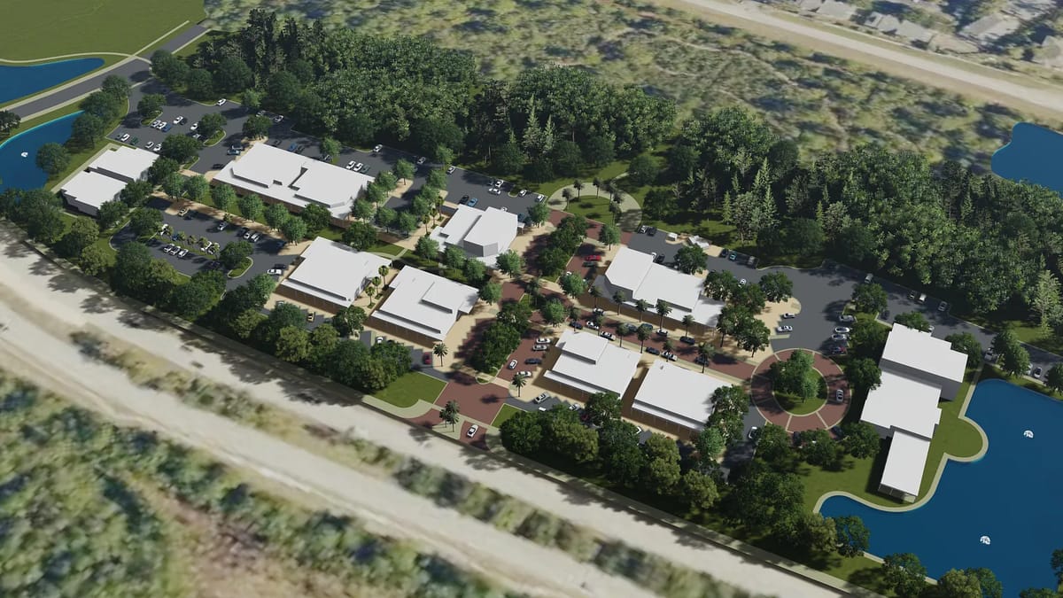 Aerial view of a complex with multiple buildings, parking, green spaces, lake, and pathways.