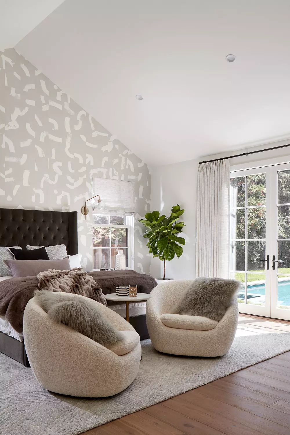Bedroom with king-sized bed, armchairs, coffee table, large window, and a potted plant with outdoor view