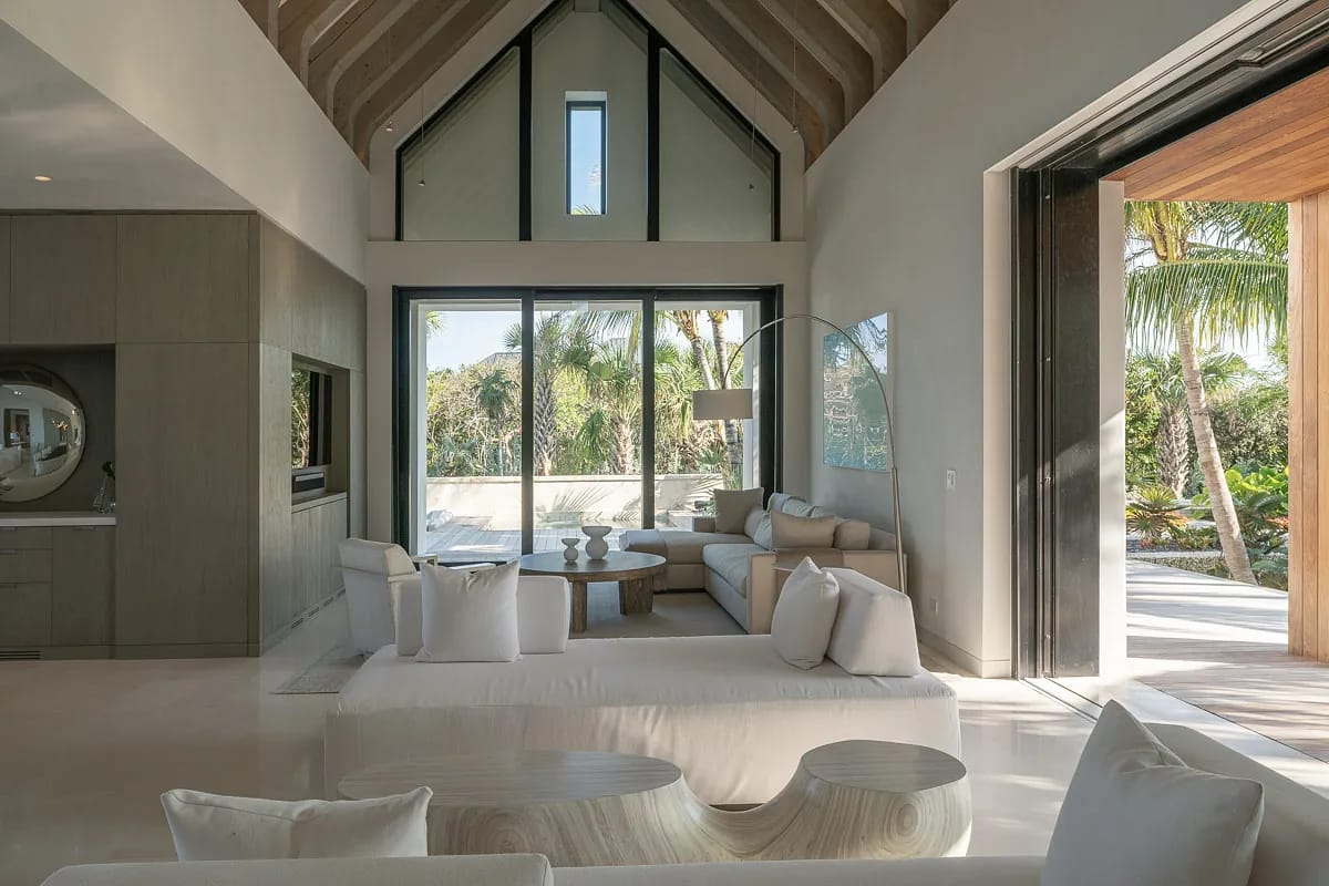 Living room with light sofas, round coffee table, large windows, and access to an outdoor area