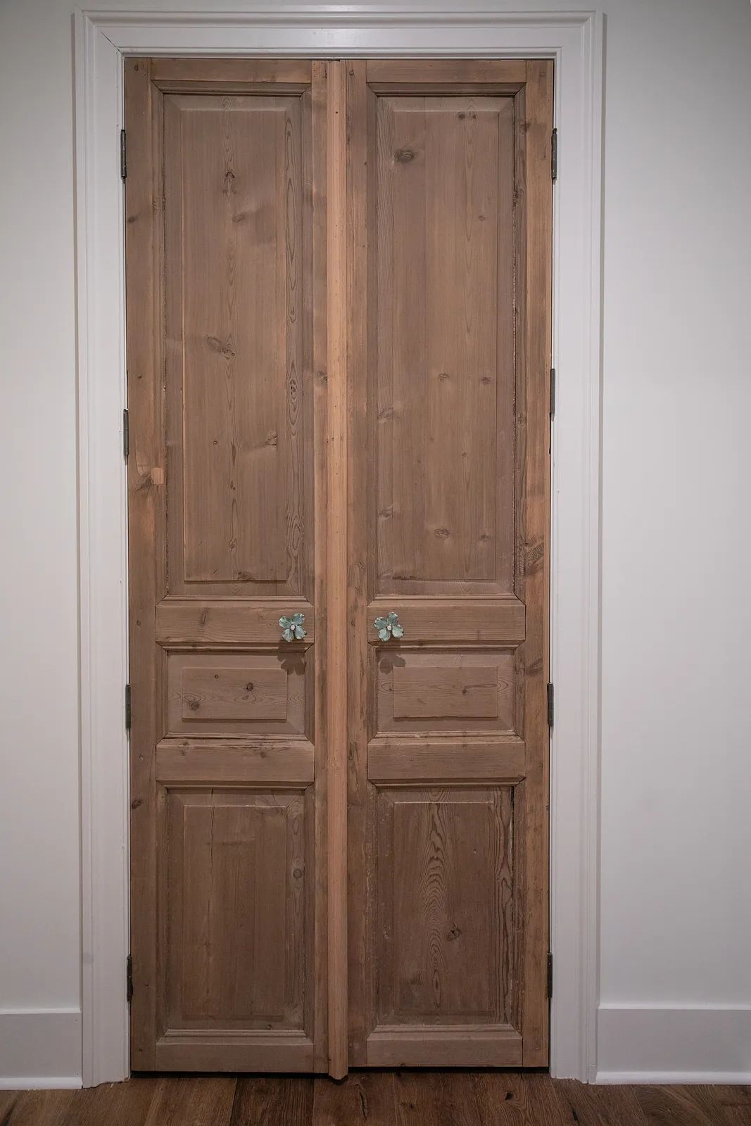 Double wooden doors with panel design, metal handles, and hardwood flooring.