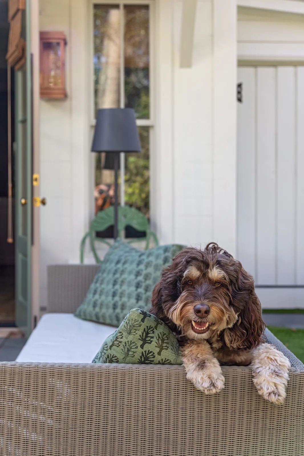 Patio with outdoor sofa, green cushions, side table, and black floor lamp.