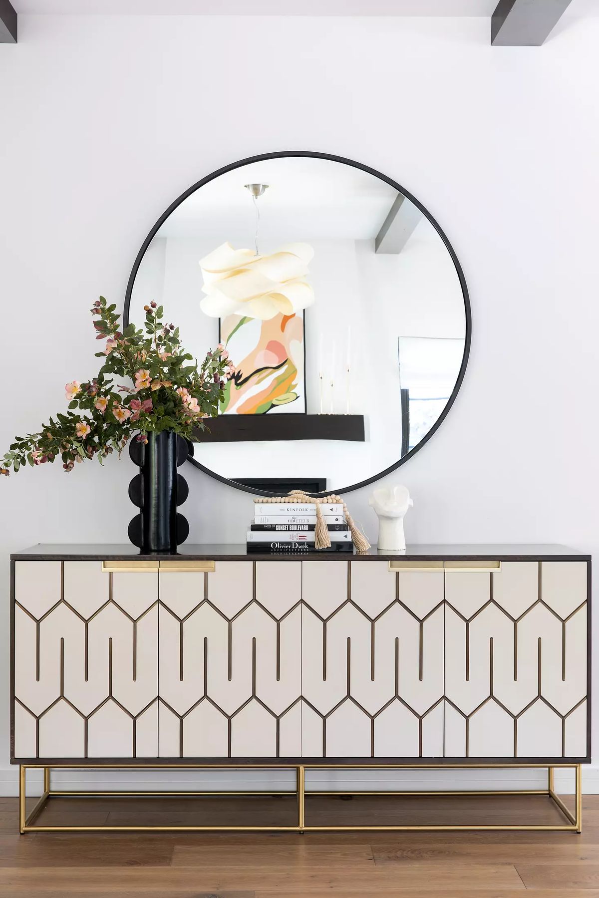 Decorative area with patterned console table, flowers, mirror, and colorful artwork.