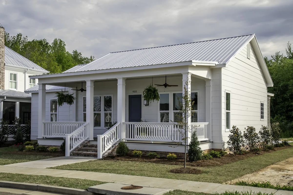 Front exterior of a house with white siding, gray roof, porch, and landscaping.