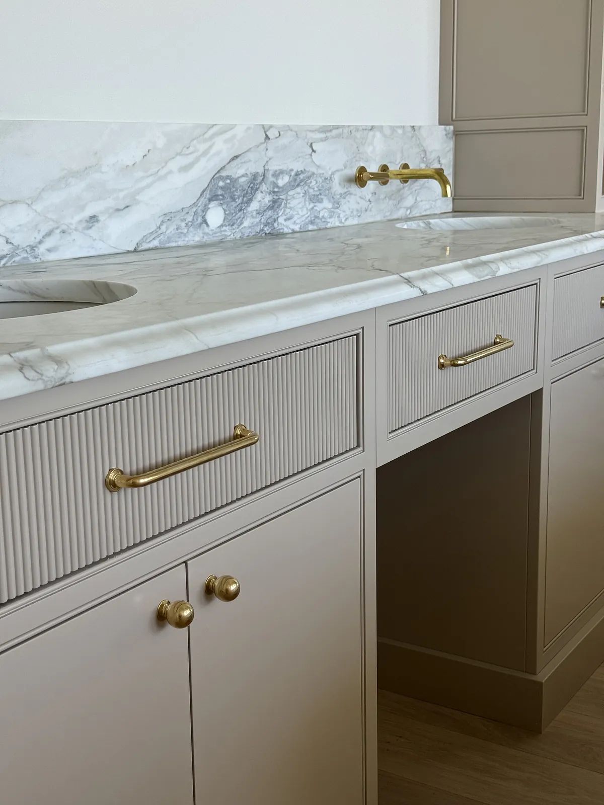 Powder room with vanity, marble countertop, gold faucet, and paneled walls.