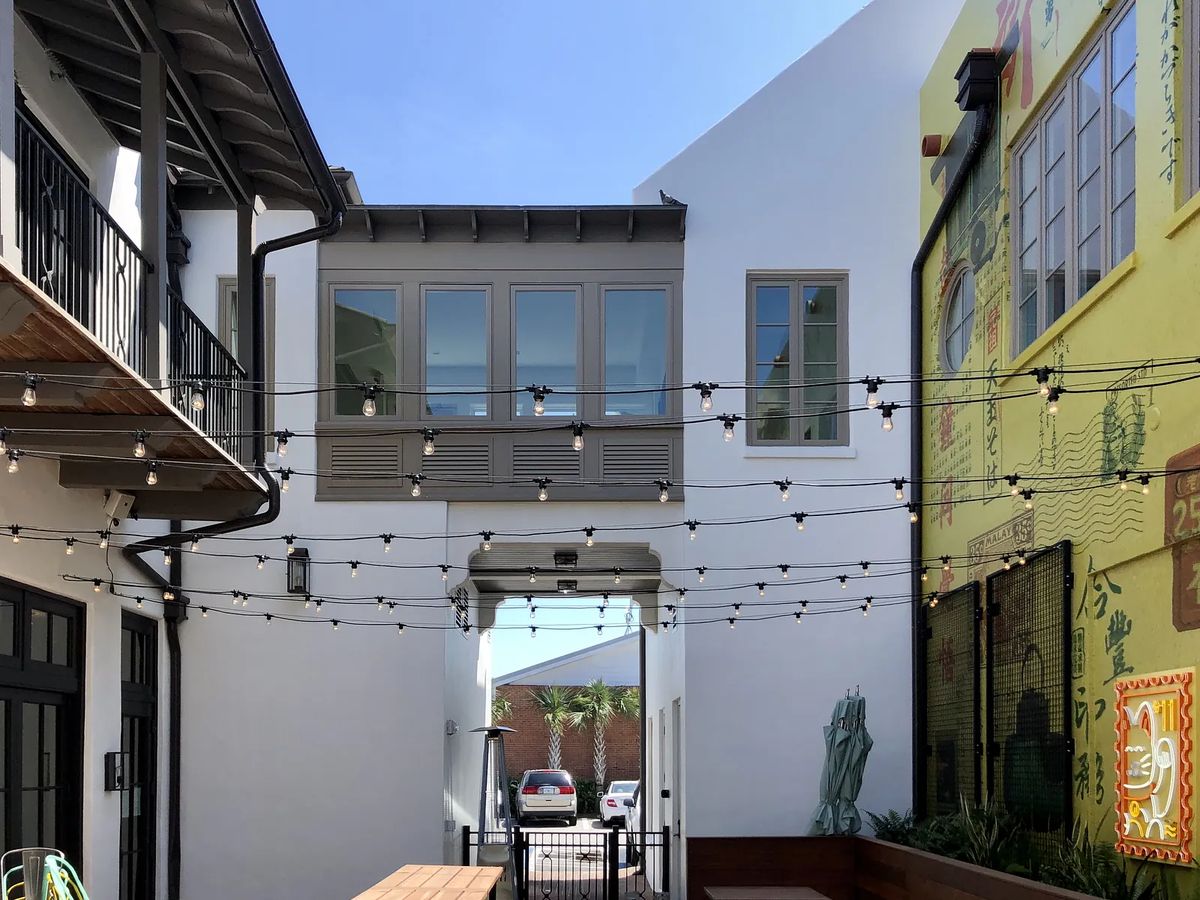 Outdoor patio with wooden deck, string lights, and a view of a building with murals.