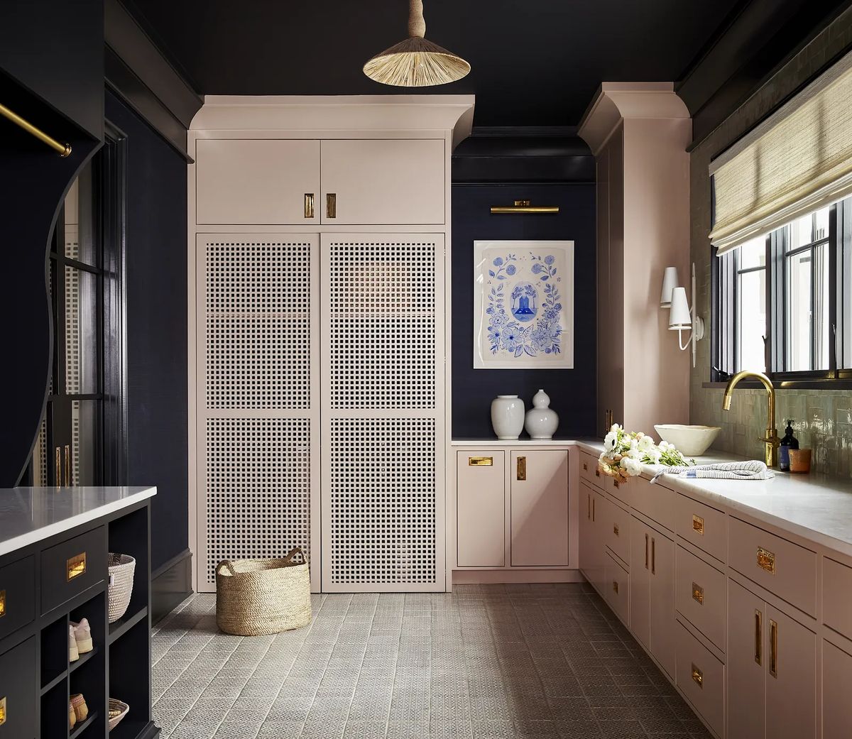 Kitchen with dark ceiling, light cabinetry, artwork, countertop, brass faucet, and woven basket.