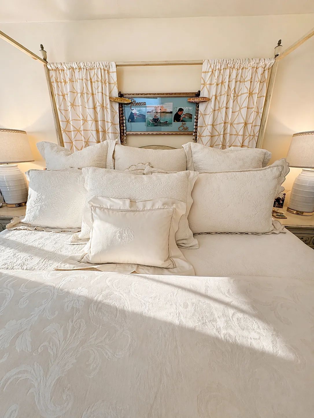 Bedroom with canopy bed, decorative pillows, blue table lamps, and geometric curtains
