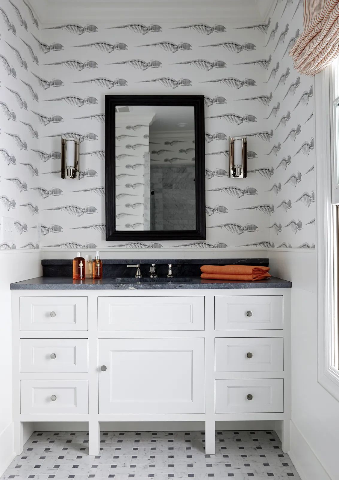 Bathroom with white vanity, black countertop, fish-patterned wallpaper, and orange towel