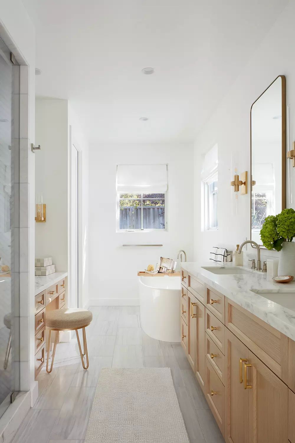 Bathroom with freestanding tub, double vanity, marble countertops, and natural light from window.