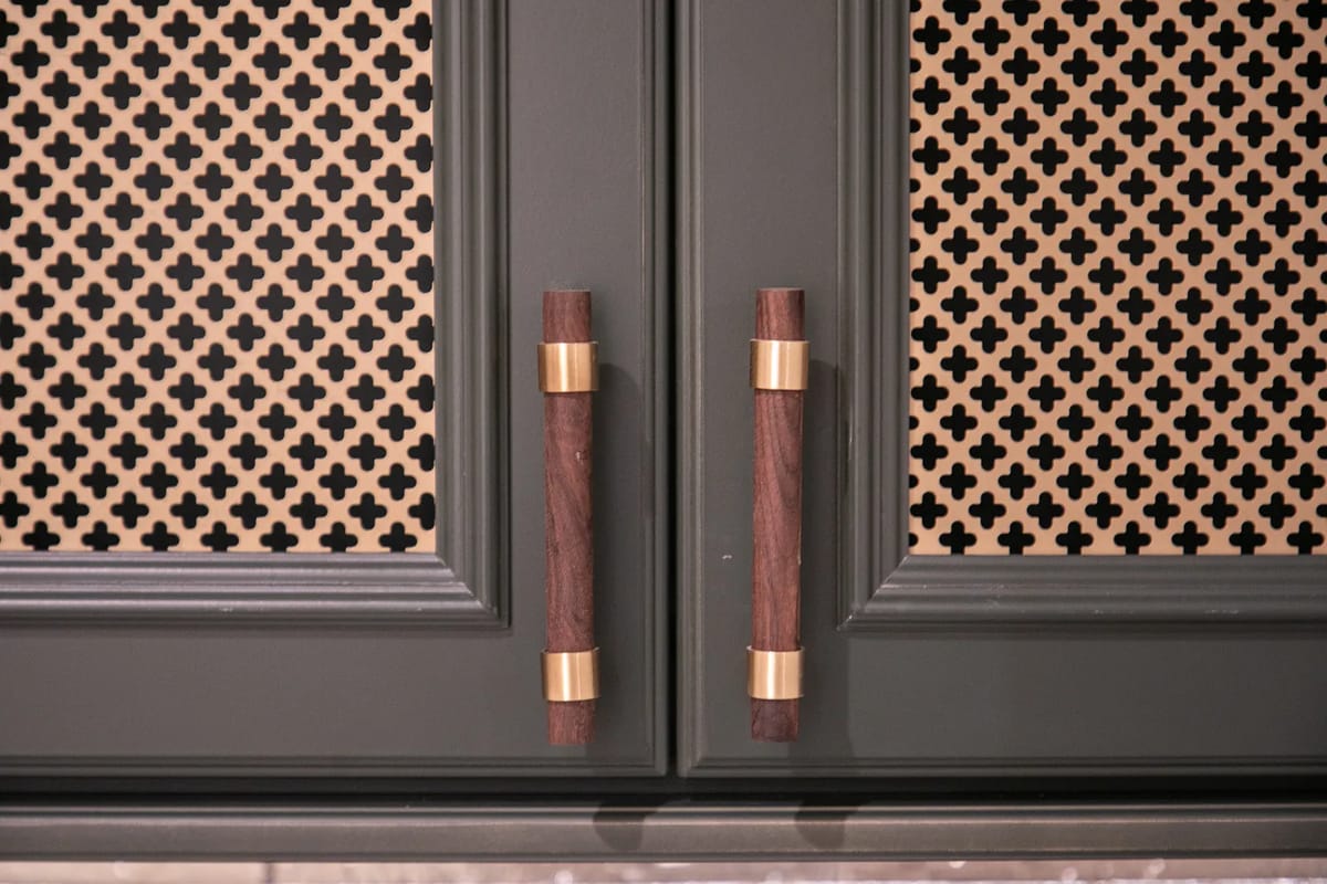 Kitchen cabinet doors with dark green panels, gold hardware, and cane webbing inserts.