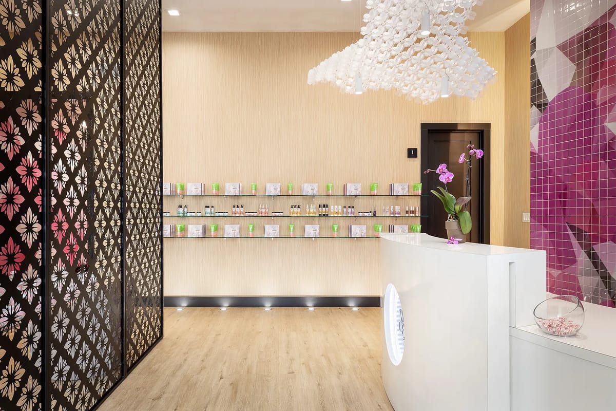 Interior space with white reception desk, floral wall, product shelving, and large light fixture.