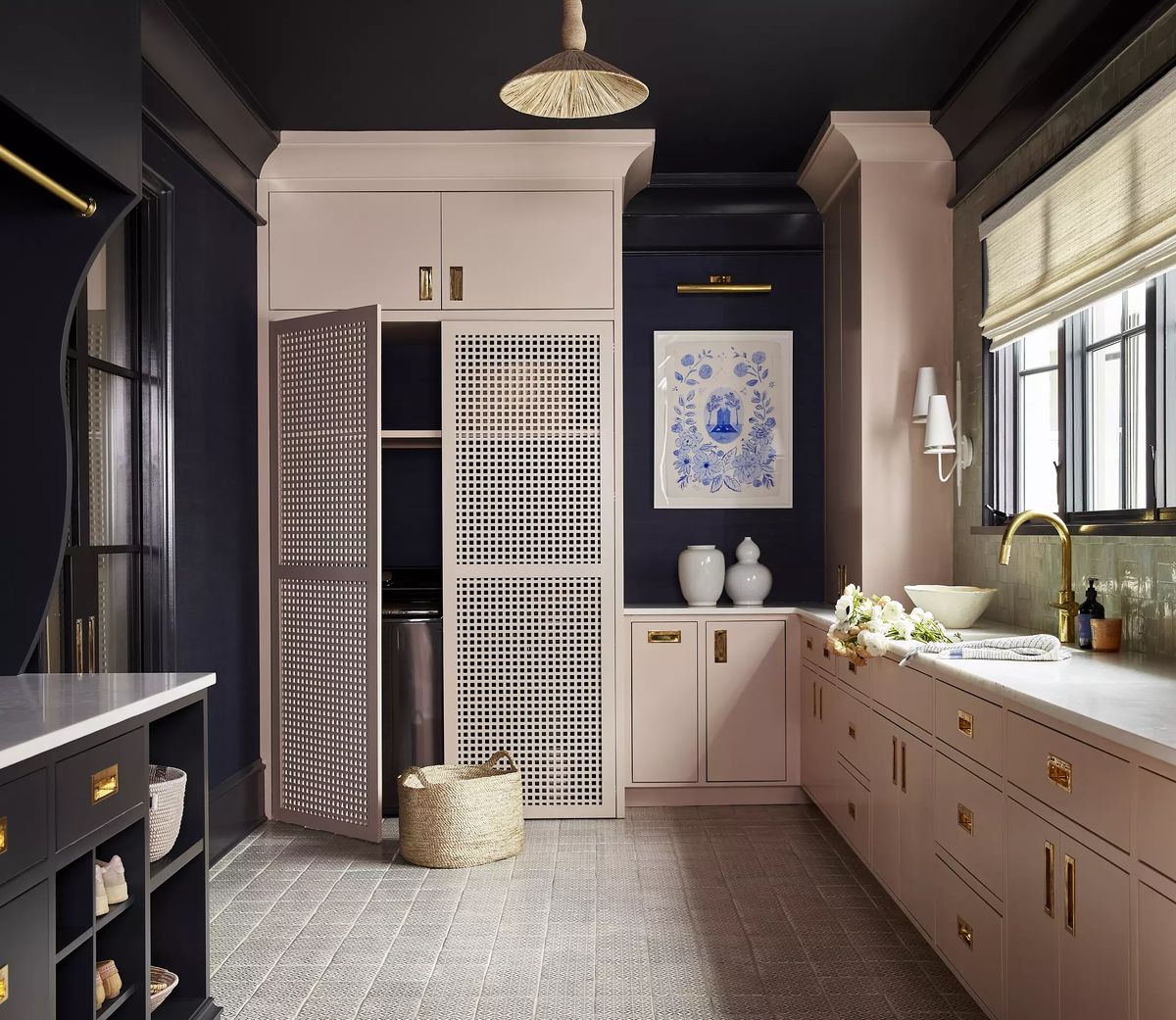 Laundry room with pink cabinetry, utility sink, washer, large window, and decorative wall art.