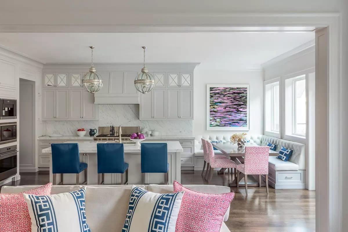 Kitchen with gray cabinetry, marble backsplash, island with bar stools, and dining nook.