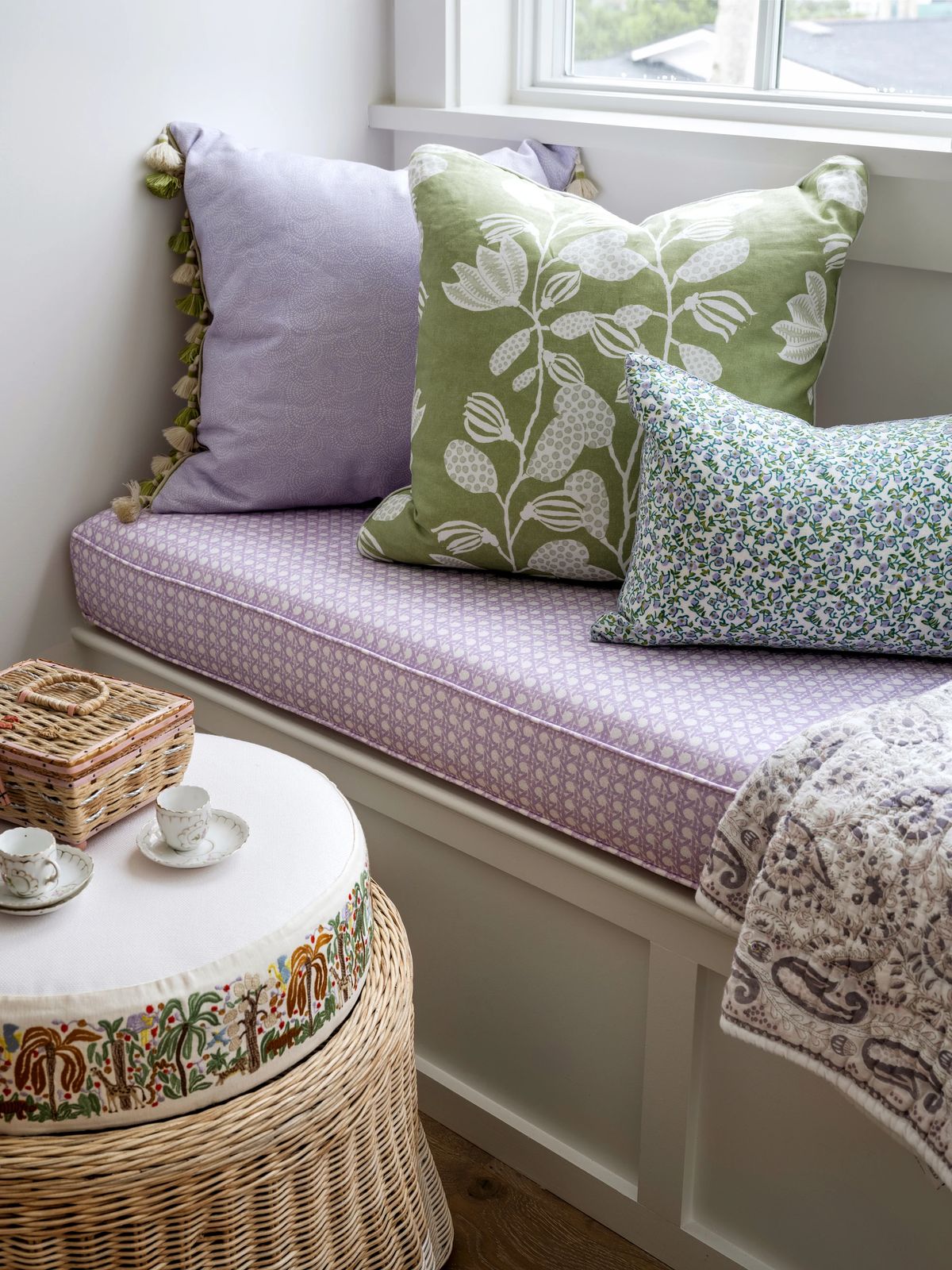 Cozy nook with built-in bench, decorative pillows, woven table, and natural light from a window.