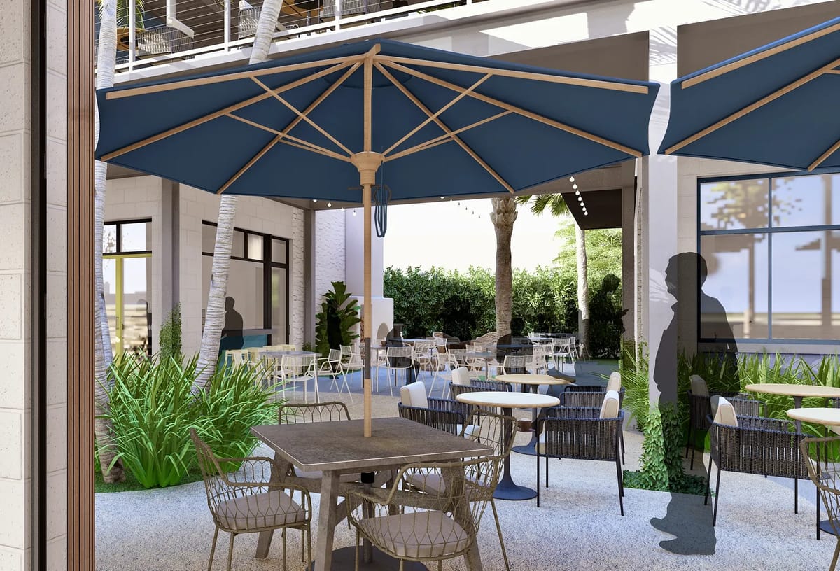 Patio with tables, chairs, blue umbrellas, and plants along the perimeter.