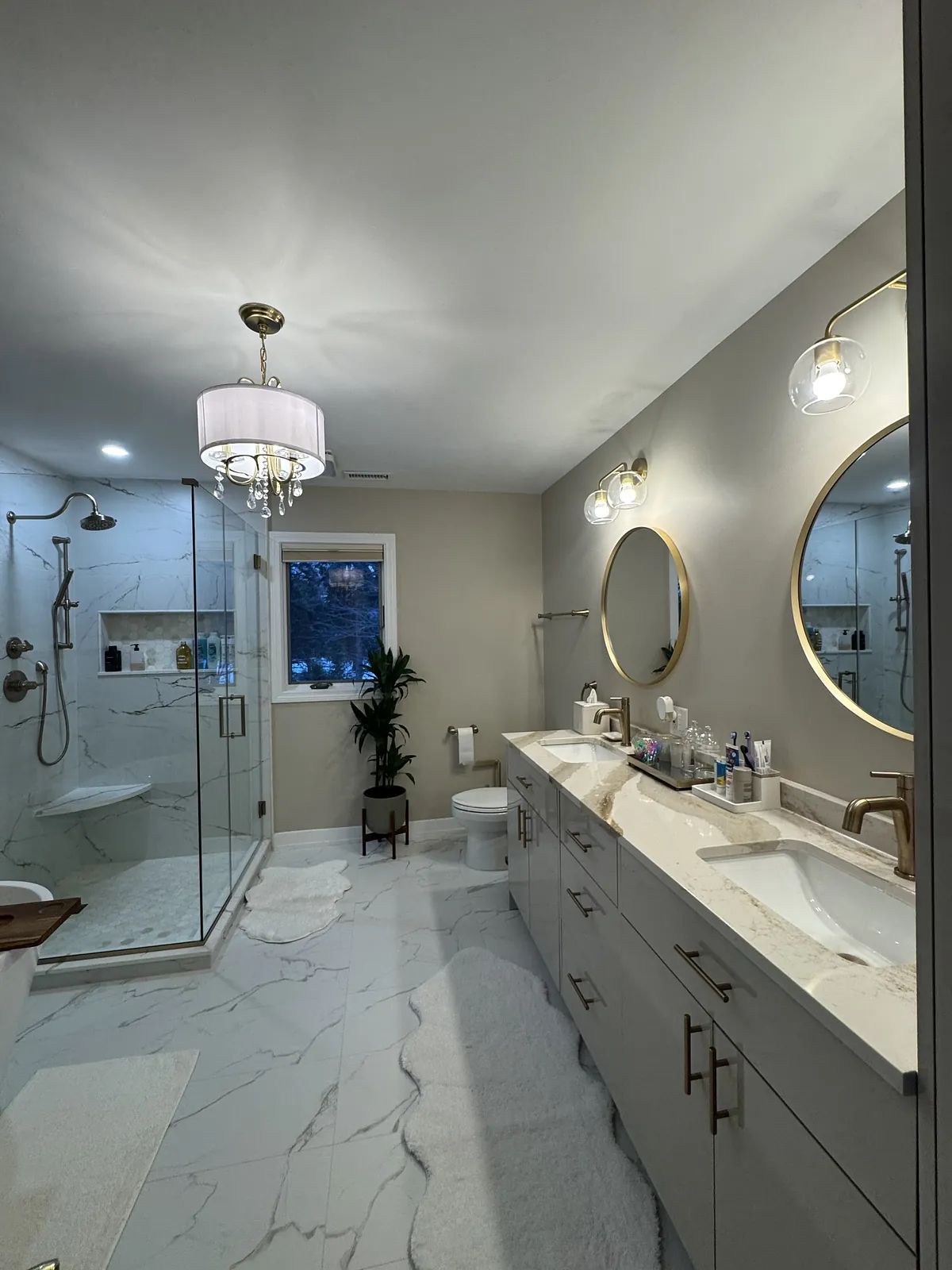 Bathroom with double sink vanity, marble countertops, glass shower, freestanding bathtub, and circular mirrors