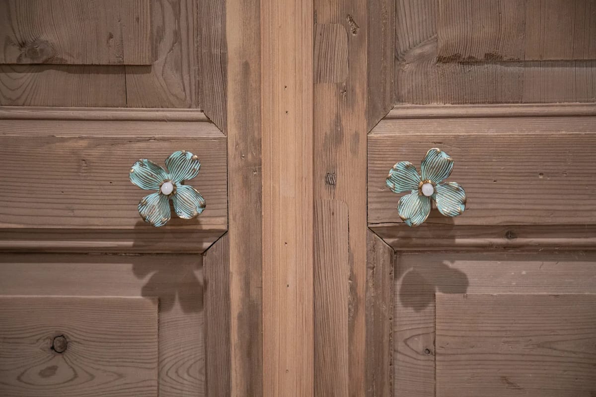 Close-up of decorative wooden doors with flower-shaped handles.