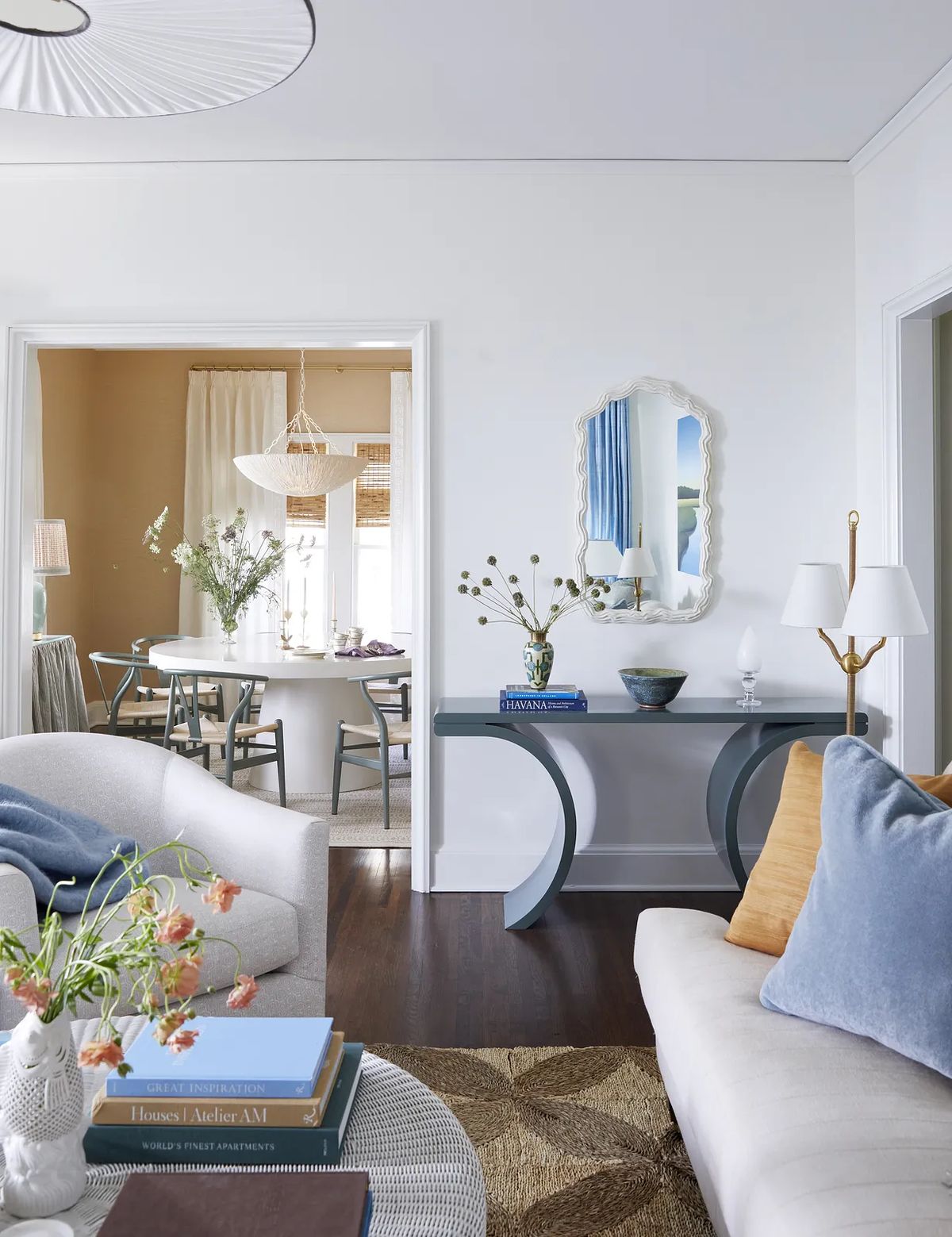 Living room with gray sofa, round coffee table, console table, mirror, and adjacent dining area.