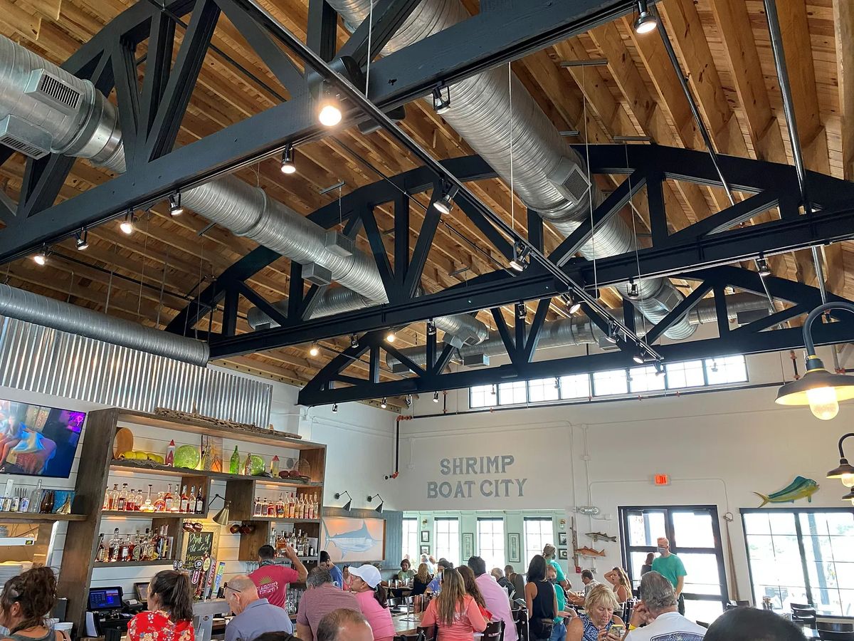 Dining room with wooden bar, metal beams, large windows, and seating area for guests.