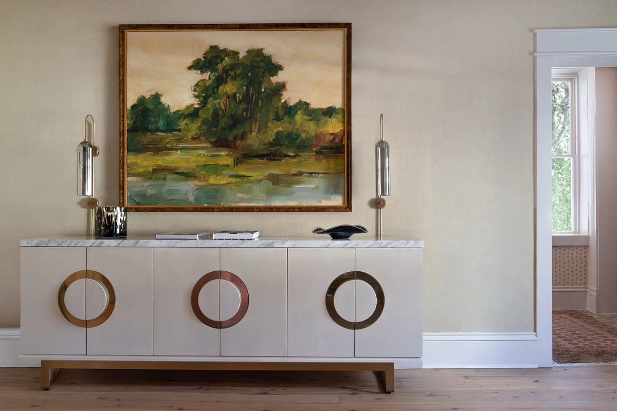 Foyer with beige walls, wooden floor, sideboard, landscape painting, and a window.