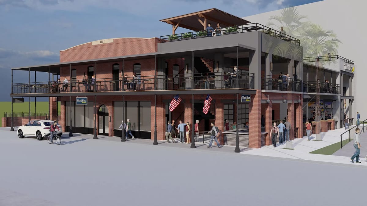 Multi-level building with brick façade, balcony, outdoor seating, and American flags.