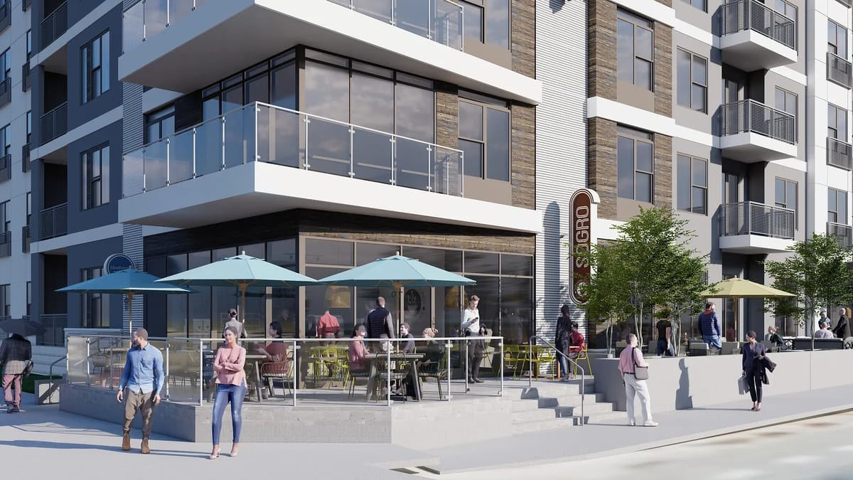 Exterior front view of a multi-story building with large windows, patios, and people socializing.