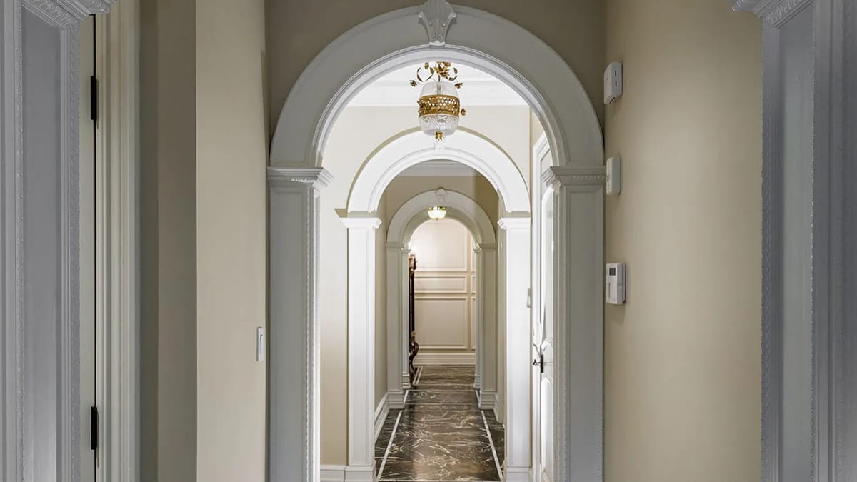 Hallway with arched doorways, patterned stone floor, and decorative light fixtures.