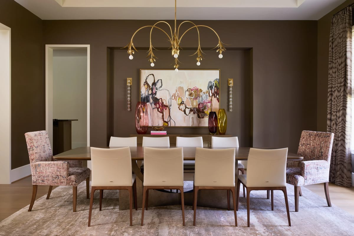 Dining room with large table, eight chairs, mid-century chandelier, and abstract artwork on brown walls.