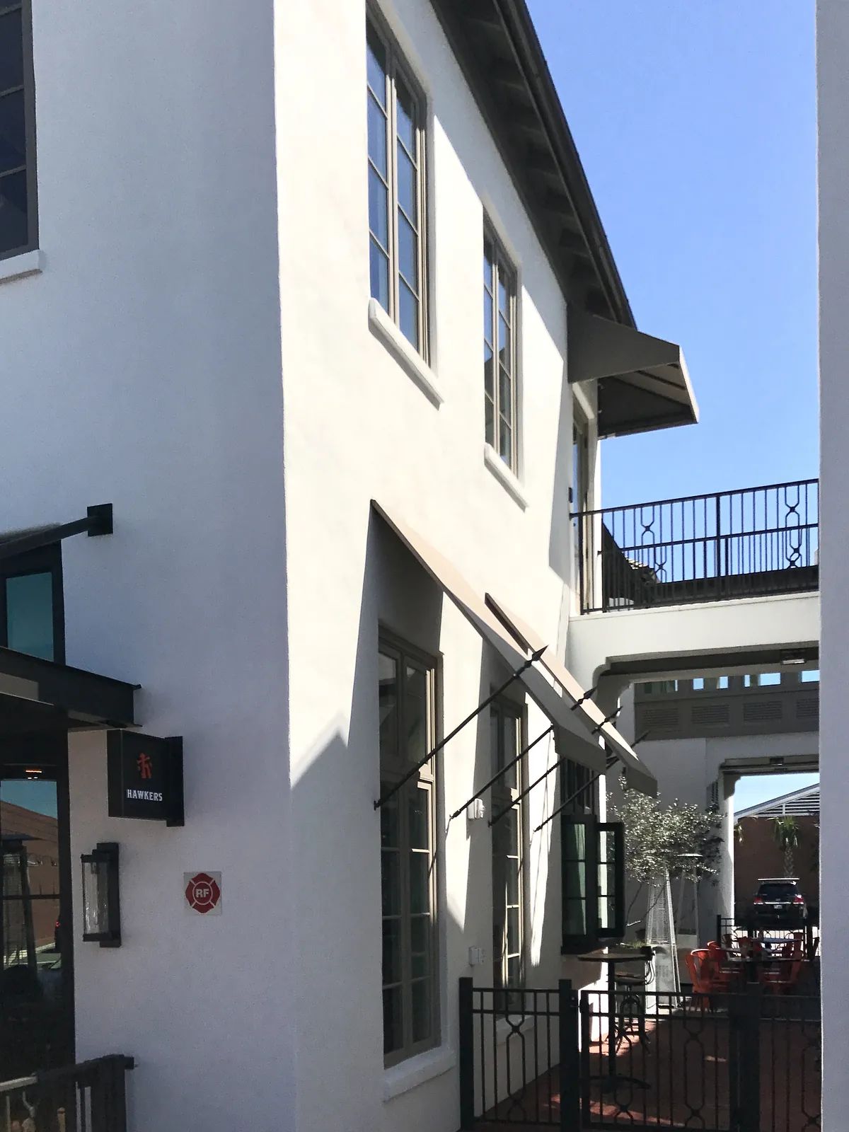 Exterior view of a building with white stucco, multiple windows, and wrought iron railing.