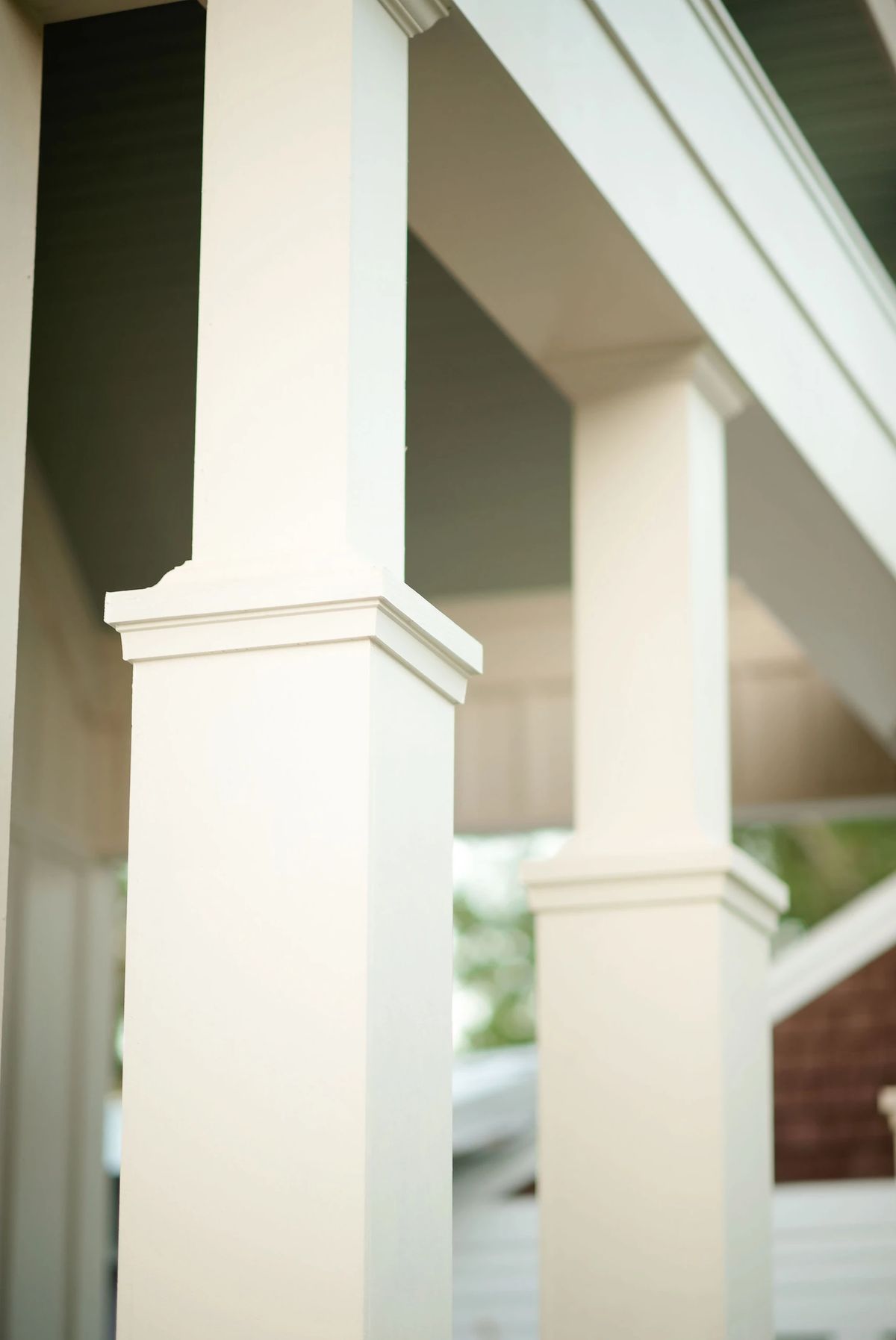 Exterior porch with white columns and muted green ceiling.