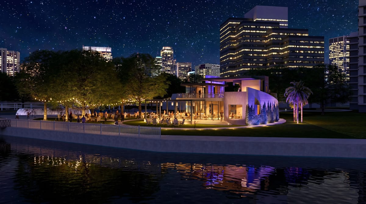 Curved building exterior with large glass windows, outdoor seating, and city skyline at night.