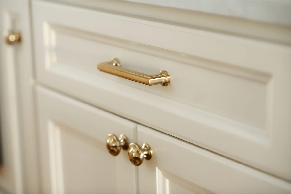 Kitchen cabinet with cream panels, gold handles, and classic design.
