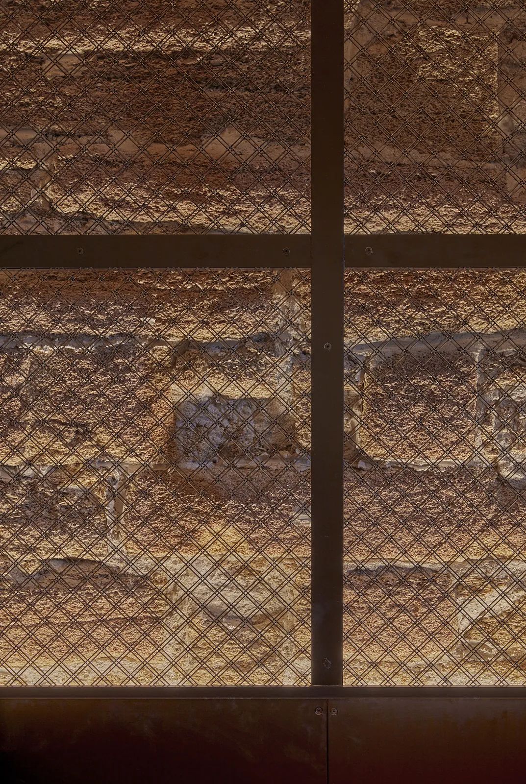 Textured stone wall with a metal grid overlay.