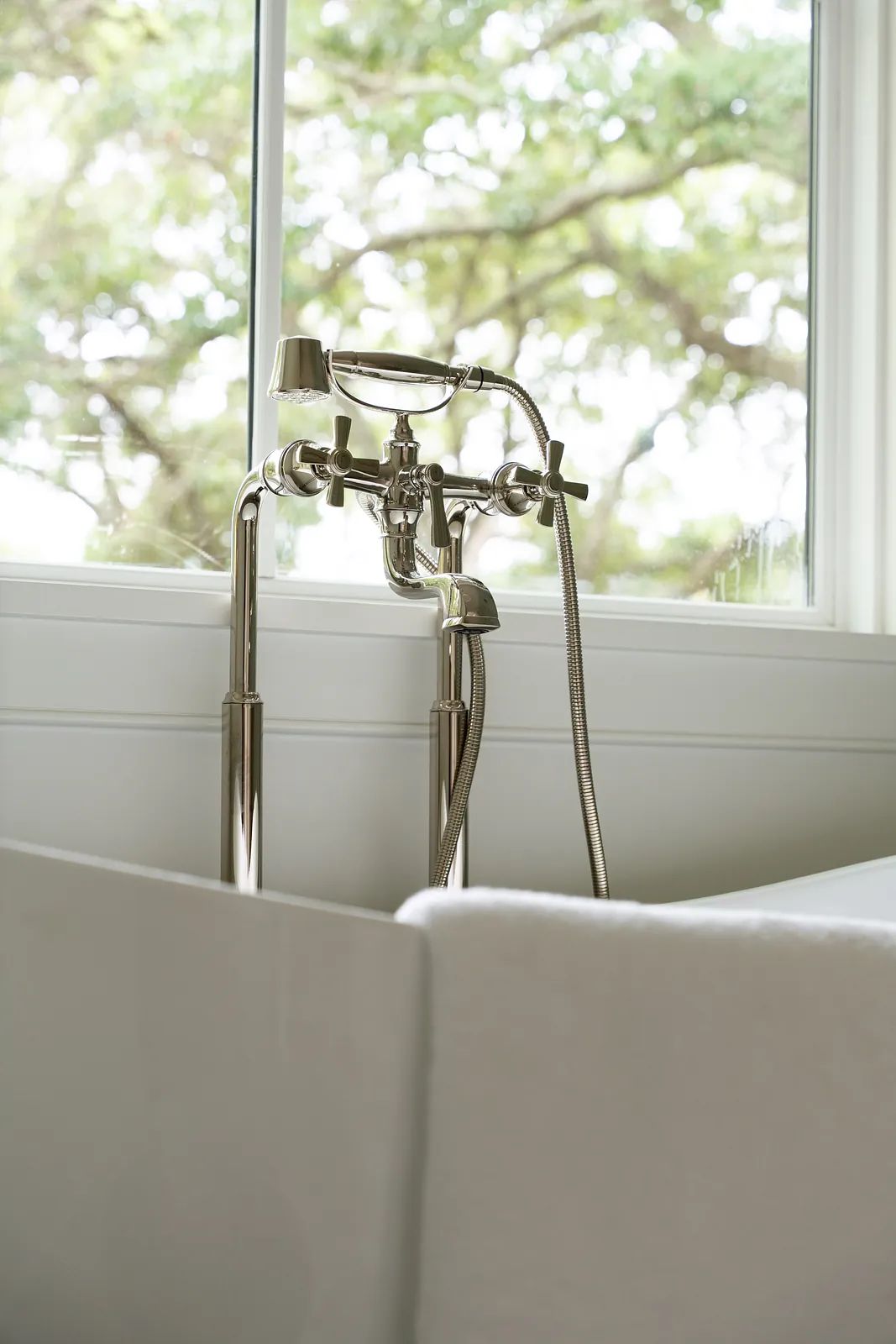 Bathroom with freestanding bathtub, chrome faucet, and large window for natural light.
