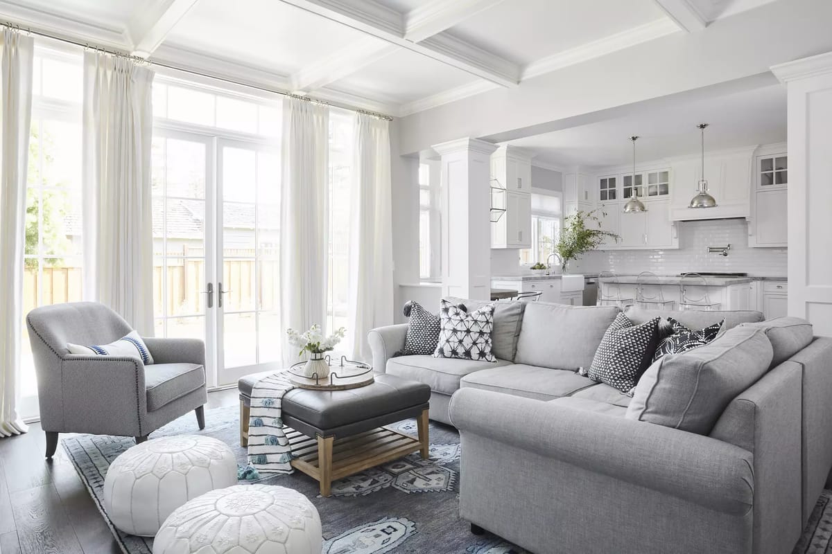 Living room with gray sofa, armchair, coffee table, area rug, and natural light from windows.
