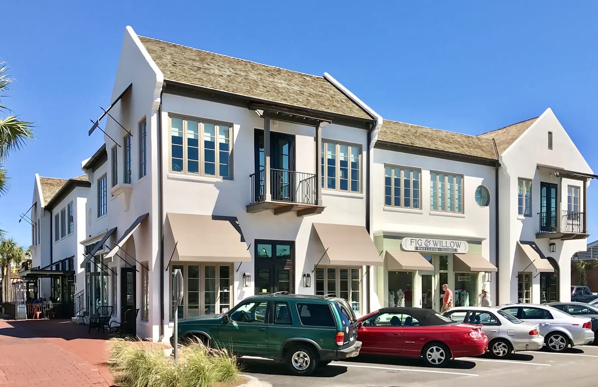 Commercial building facade with blue windows, awnings, and parked cars.