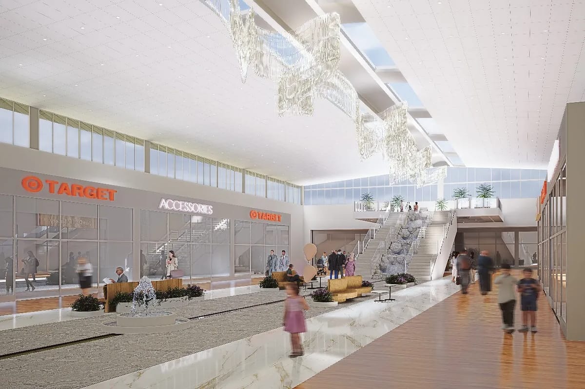 Interior atrium with glass walls, fountain, seating, plants, and staircase.