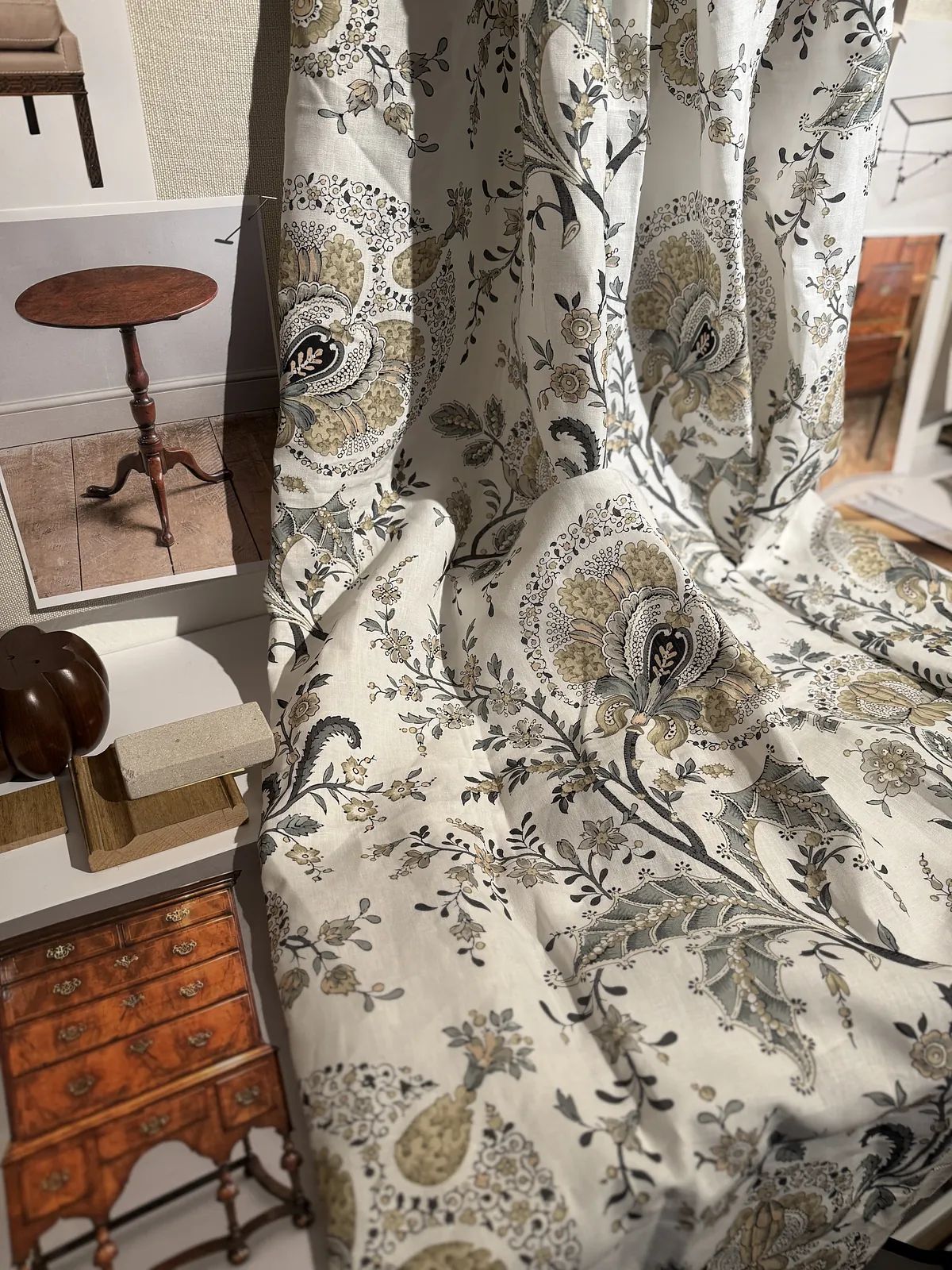 Fabric swatches with floral patterns, a round wooden table, and various furniture samples displayed.