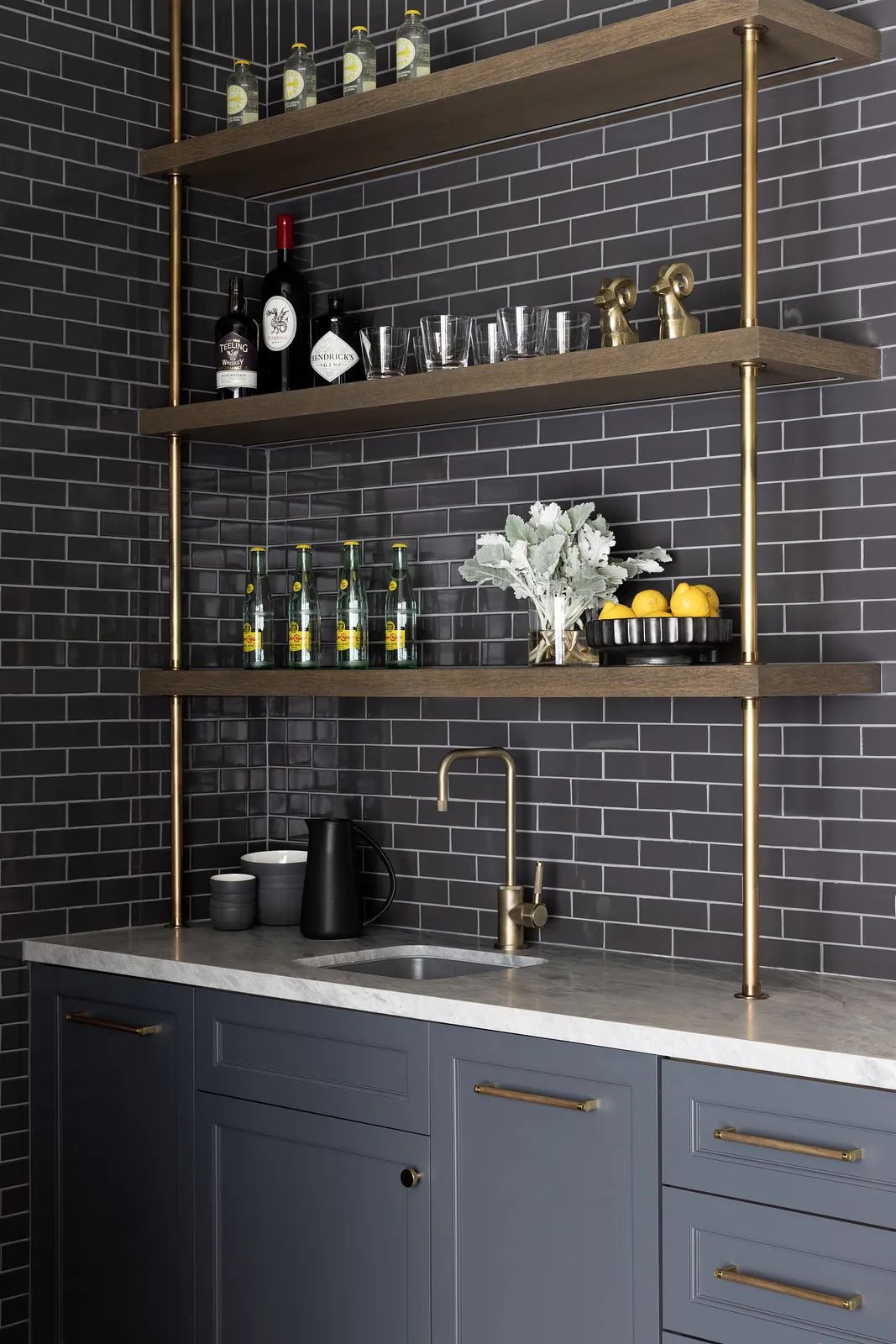 Butler's pantry with gray cabinetry, white marble countertop, open shelving, and dark gray tile backsplash.