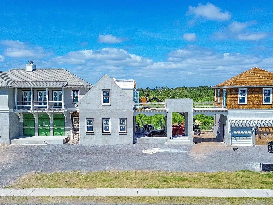 Exterior view of two under-construction residential buildings with unfinished walls and roofing.